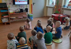 Dzieci oglądają prezentację multimedialną dotyczącą tradycji świątecznych.